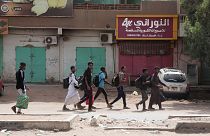 طلاب أمام متاجر مغلقة في الخرطوم في ثالث يوم من الاشتباكات