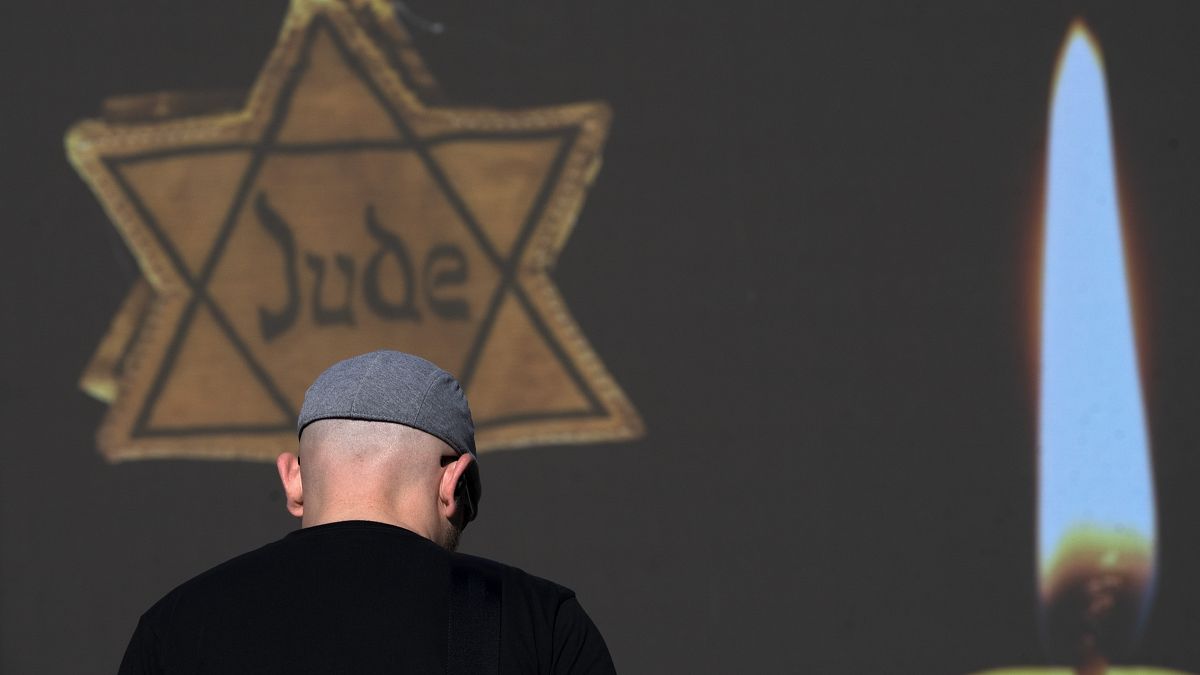 Прохожий на фоне плаката с желтой Звездой Давида и надписью "еврей" на немецком. Рамат-Ган, Израиль