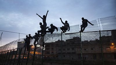 Sub-Saharan migrants climb over a metallic fence that divides Morocco and the Spanish enclave of Melilla, March 29, 2014