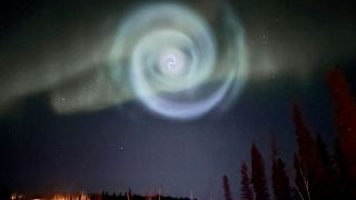 عکس ارائه شده توسط کریستوفر هیدن، یک مارپیچ آبی روشن شبیه کهکشان در میان شفق قطبی برای چند دقیقه در آسمان آلاسکا ، شنبه، ۱۵ آوریل ۲۰۲۳ ظاهر شد.