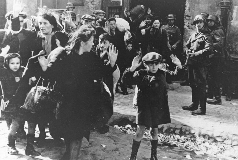 Un groupe de Juifs, dont un petit garçon, est escorté hors du ghetto de Varsovie par des soldats allemands le 19 avril 1943