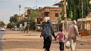 Duas mulheres e uma criança caminham por Cartum, Sudão, no dia em que foi decretado um cessar-fogo no país