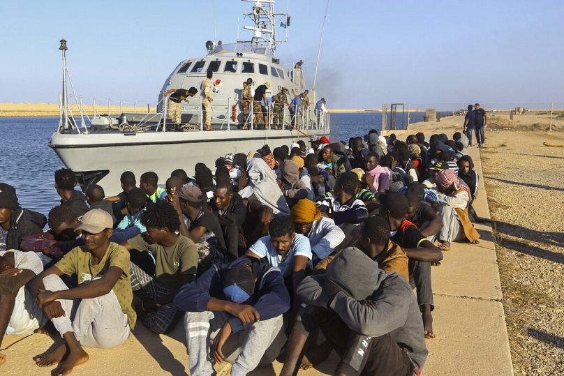 مهاجرون ناجون يجلسون بجانب قارب خفر السواحل في مدينة الخمس، ليبيا، بعد إنقاذهم، الثلاثاء، 1 تشرين الأول/ أكتوبر 2019.