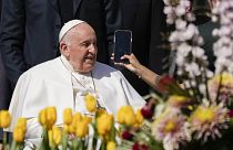 Pope Francis takes on AI - here pictured leaving his weekly general audience in St. Peter's Square, at the Vatican, while a woman holds a phone - 12 April 2023