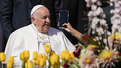 Pope Francis takes on AI - here pictured leaving his weekly general audience in St. Peter's Square, at the Vatican, while a woman holds a phone - 12 April 2023