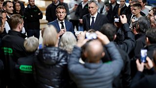 French President Emmanuel Macron, center, next to Mathis CEO Frank Mathis, right, speaks to employees during a visit to Mathis, company specialized in large wooden buildings.