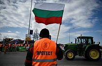 Un agriculteur agite un drapeau lors d'une action de blocage sur le Pont du Danube, qui marque la frontière entre la Roumanie et la Bulgarie. (29 mars 2023)
