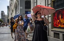 A woman holds an umbrella to shelter from the sun during a hot sunny day in Madrid, Spain, Monday, July 18, 2022.