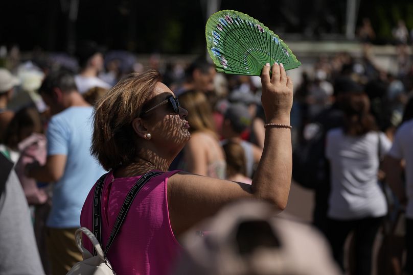 A woman uses a fan to shade herself during a heatwave in London, July 2022.