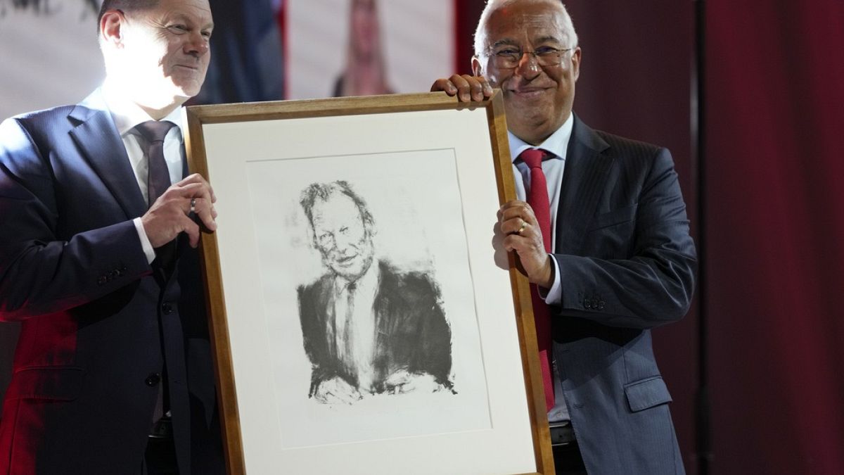 German Chancellor Olaf Scholz, left, presents Portuguese Prime Minister and Socialist Party Secretary General Antonio with a portrait of Willy Brandt.