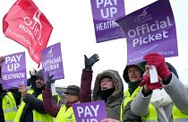 Members of the Unite union stand at a picket line near Heathrow Airport in London.