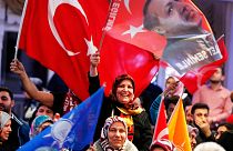 FILE - In this March 6, 2017 file photo women wave a Turkish flag and a flag showing President Erdogan, near Frankfurt