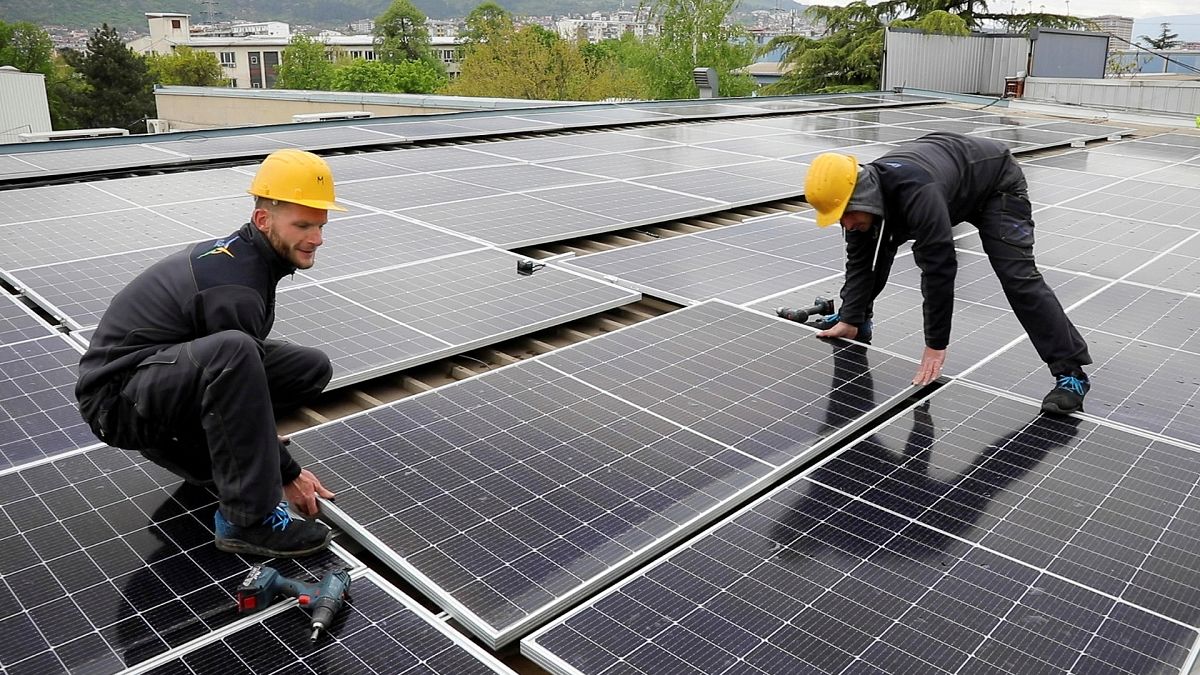 Workers install solar panels on an office building in Skopje, North Macedonia 19 April 2023.