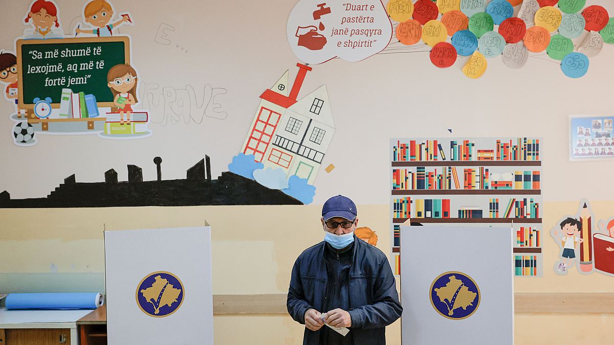 Un hombre sostiene su papeleta en las elecciones municipales de Pristina, capital de Kosovo, el domingo 14 de noviembre de 2021.