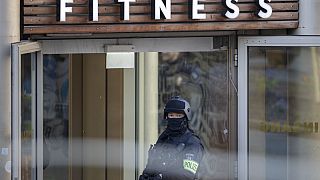 Polizeibeamter steht vor dem Fitness-Studio in Duisburg, in dem die Messerattacke stattfand