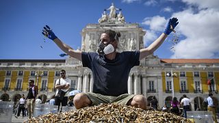 German environmental activist, Andreas Noe, throws cigarette butts as he sits on top of a pile of them, collected in one week, at Comercio square in Lisbon 24/04