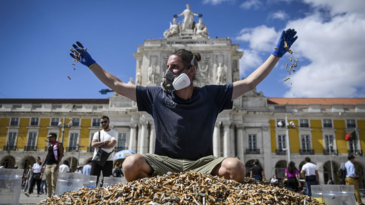 Немецкий активист Андреа Ноэ на куче окурков в центре Лиссабона