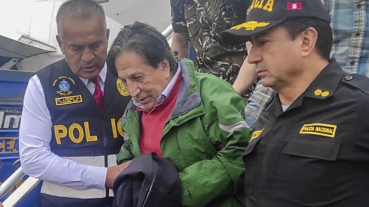 Бывший президент Перу Алехандро Толедо спускается с самолета в сопровождении агентов Интерпола