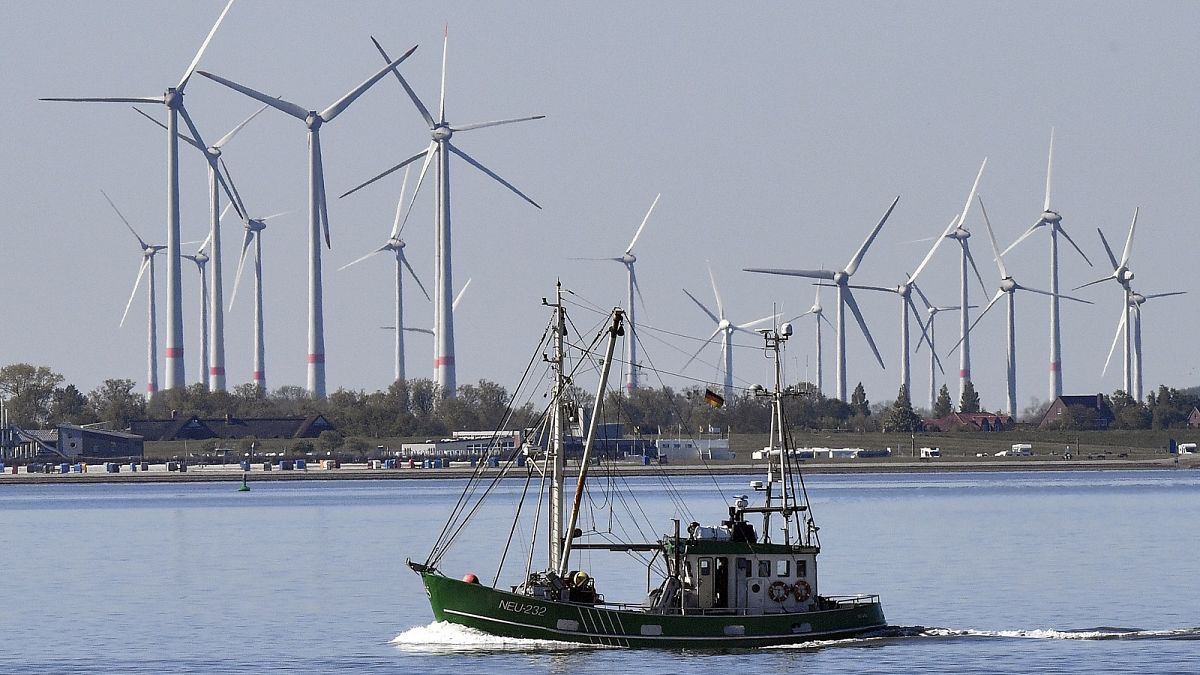 A fisher boat passes wind turbines between the island Langeoog and Bensersiel at the North Sea coast in Germany, on May 15, 2019