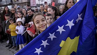A Kosovo Albanian child holds the Kosovo flag during the military parade celebrations to mark the 15th anniversary of Kosovo's declaration of independence in Pristina in 2023.