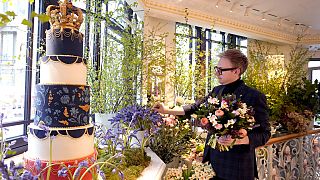 Philip Hamond, florista del Hotel Dorchester, trabaja junto a un expositor que muestra una tarta temática de la Coronación y arreglos florales en el Hotel Dorchester, Londres