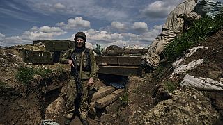 A Ukrainian soldier smiles standing in a trench on the frontline in the village of New York, Donetsk region, Ukraine, Monday, April 24, 2023.