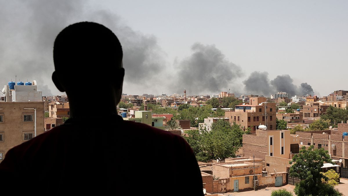 Um homem observa a coluna de fumo sobre a capital do Sudão