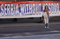 A woman passes by a billboard reading: ''Serbia without Kosovo would be like a human without heart'' at a protest in Belgrade. 24 March 2023