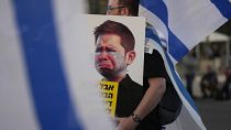 متظاهر يرفع رسم كاريكاتوري لنجل نتنياهو خلال مظاهرة في تل أبيب