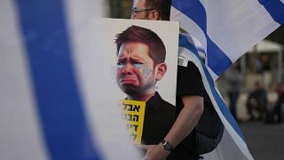 Egy kormányellenes tüntető a Netanjahu-fiú karikatúrájával
