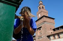 Una mujer se refresca en una fuente pública del Castillo Sforza, en Milán, Italia.
