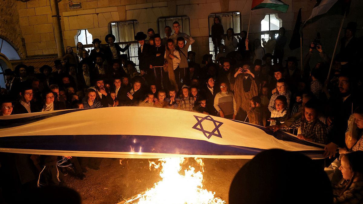 أعضاء من الحركة يحرقون أعلام إسرائيل ويلوحون بالأعلام الفلسطينية 