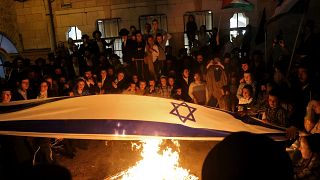 أعضاء من الحركة يحرقون أعلام إسرائيل ويلوحون بالأعلام الفلسطينية 