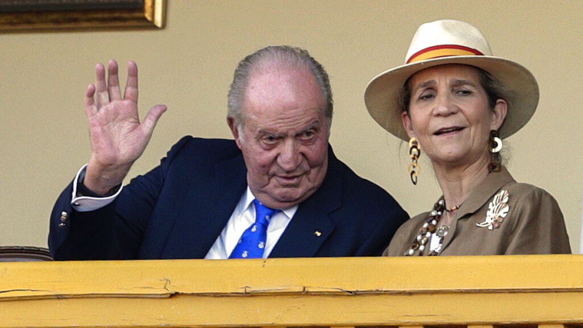 Spain's former King Juan Carlos, left, waves next to his daughter Princess Elena during a bullfight at the bullring in Aranjuez, Spain