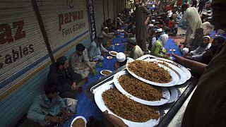 يتلقى الناس أطباق طعام مجانية وزعها متطوعون لتناول الإفطار في أحد الأسواق، في بيشاور، باكستان،16 نيسان 2023.