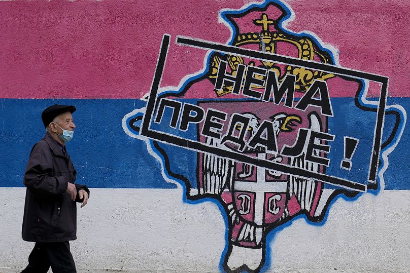 A man walks by graffiti that shows a map of Kosovo and Serbian coat of arms and flag that reads: ''No surrender!'' in Belgrade, April 26, 2023