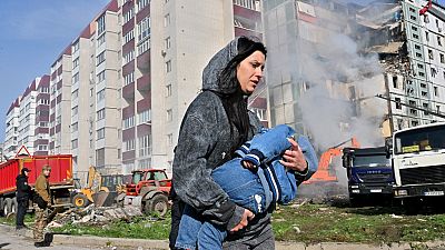 Eine Mutter trägt ihr Kind von den Flammen weg.