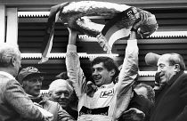 Brazilian Formula One race driver Ayrton Senna da Silva, center, holds up the winner's crown after he won the Mercedes 190 E race in Nuremberg, Germany on May 13, 1984