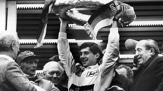 Brazilian Formula One race driver Ayrton Senna da Silva, center, holds up the winner's crown after he won the Mercedes 190 E race in Nuremberg, Germany on May 13, 1984