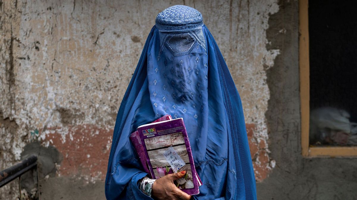 عارفه، زن ۴۰ ساله افغان، مدرسه زیرزمینی را در کابل، افغانستان ترک می‌کند.
