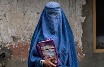 عارفه، زن ۴۰ ساله افغان، مدرسه زیرزمینی را در کابل، افغانستان ترک می‌کند.