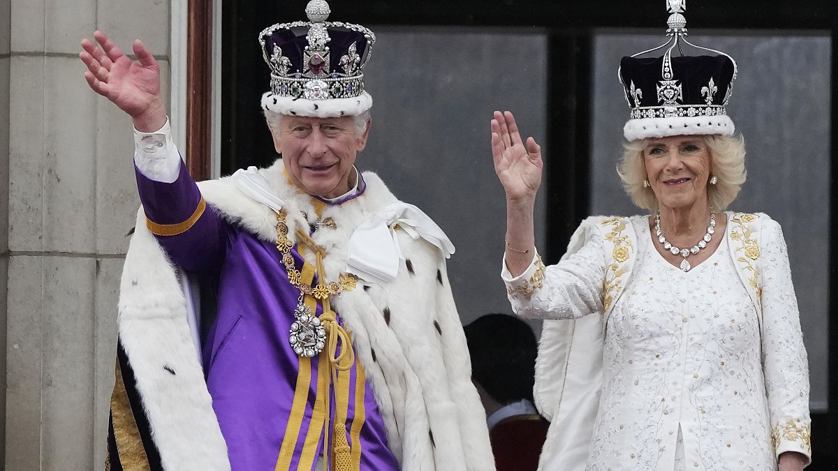 A crowned Camilla waves from the balcony of Buckingham Palace after her coronation with King Charles