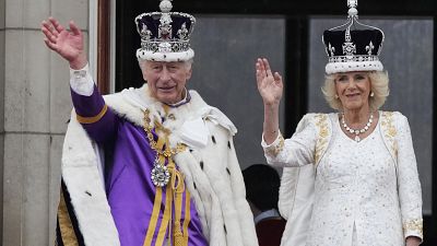 A crowned Camilla waves from the balcony of Buckingham Palace after her coronation with King Charles