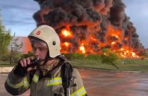رجل إطفاء يتحدث على جهاز الاتصال اللاسلكي بينما يتصاعد الدخان واللهب من خزان وقود محترق في سيفاستوبول، القرم/ 2023/04/29