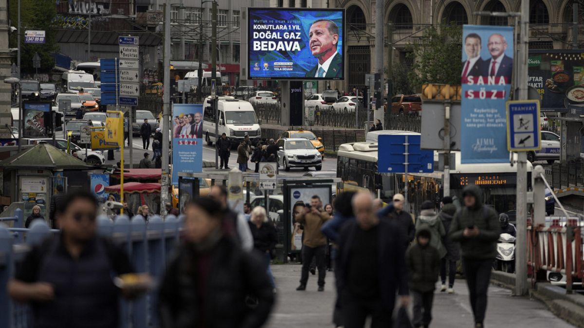 People walk by a billboard showing Turkish President and People's Alliance's presidential candidate Recep Tayyip Erdogan, in Istanbul, Turkey, Thursday, April 27, 2023. 