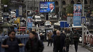 People walk by a billboard showing Turkish President and People's Alliance's presidential candidate Recep Tayyip Erdogan, in Istanbul, Turkey, Thursday, April 27, 2023. 