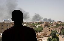 Residente de Cartum observa fumo resultante dos combates na cidade