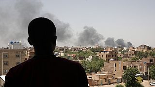 Residente de Cartum observa fumo resultante dos combates na cidade