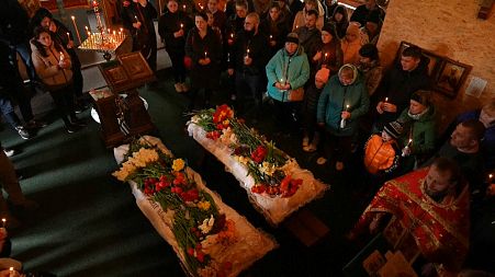 Mourners place flowers on the coffins of Sofia Shulha, 11, and Pysarev Kiriusha, 17, during a funeral in Uman, central Ukraine, Sunday, April 30, 2023. 