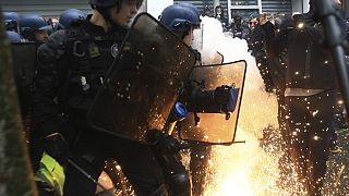Riot police officers face youths during a demonstration, Monday, May 1, 2023 in Paris. 